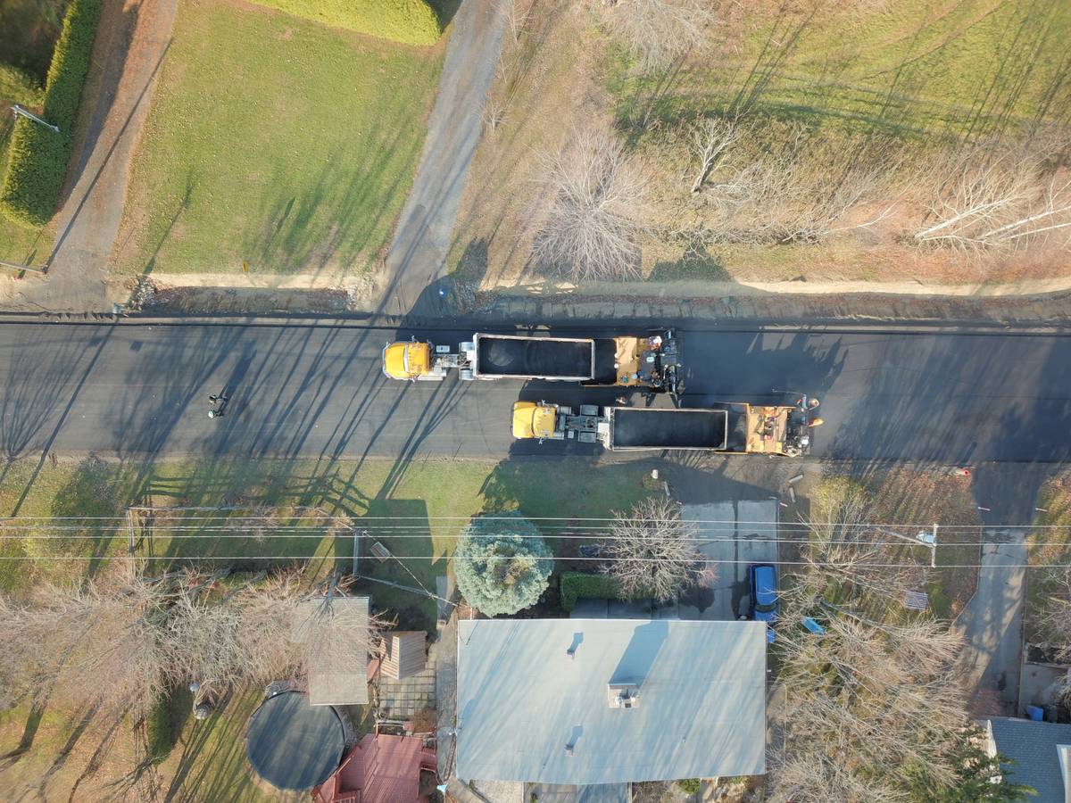 Vue du dessus de deux camions qui alimentent des paveuses