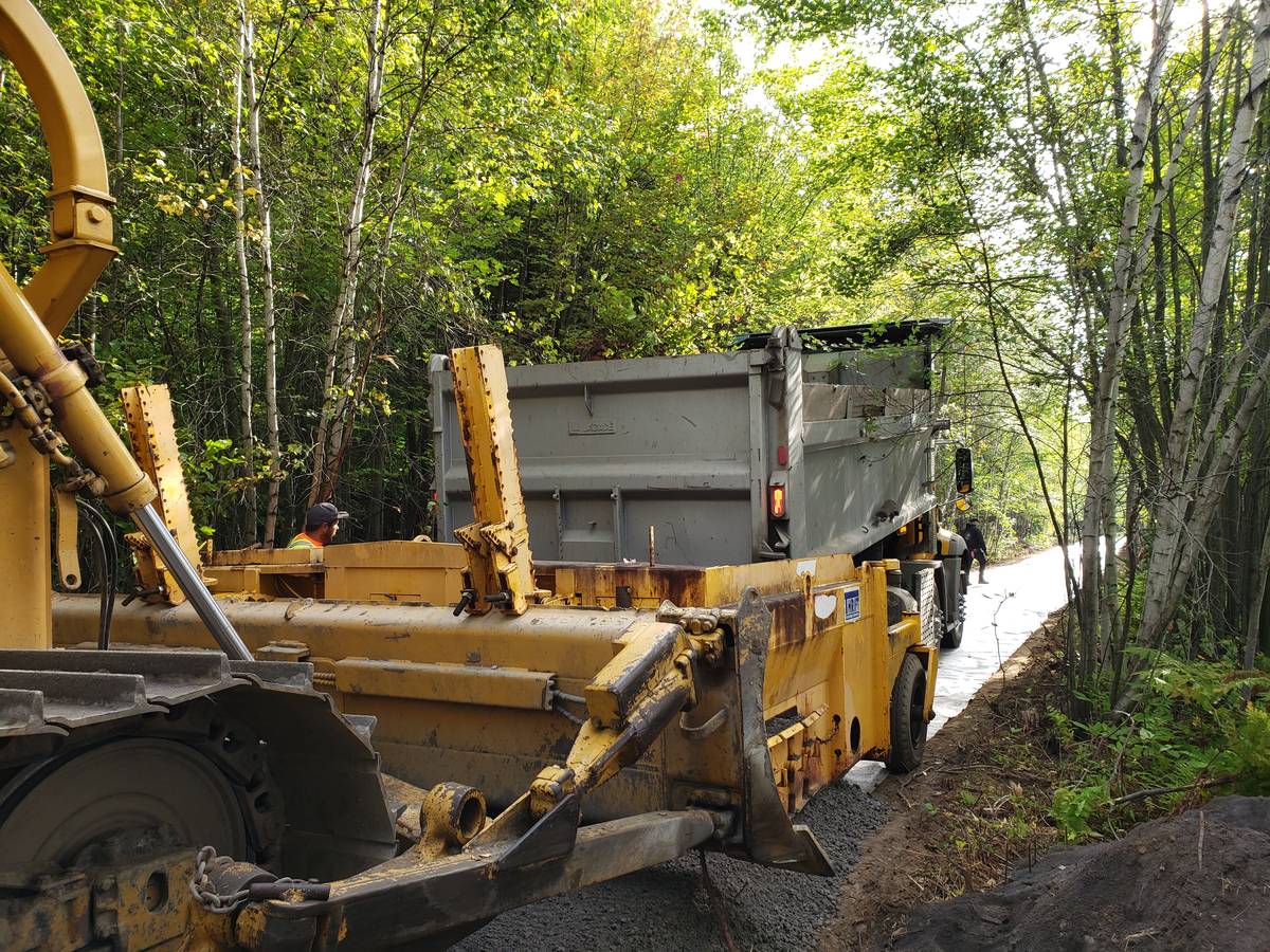 Machine et camion-benne sur un sentier en forêt